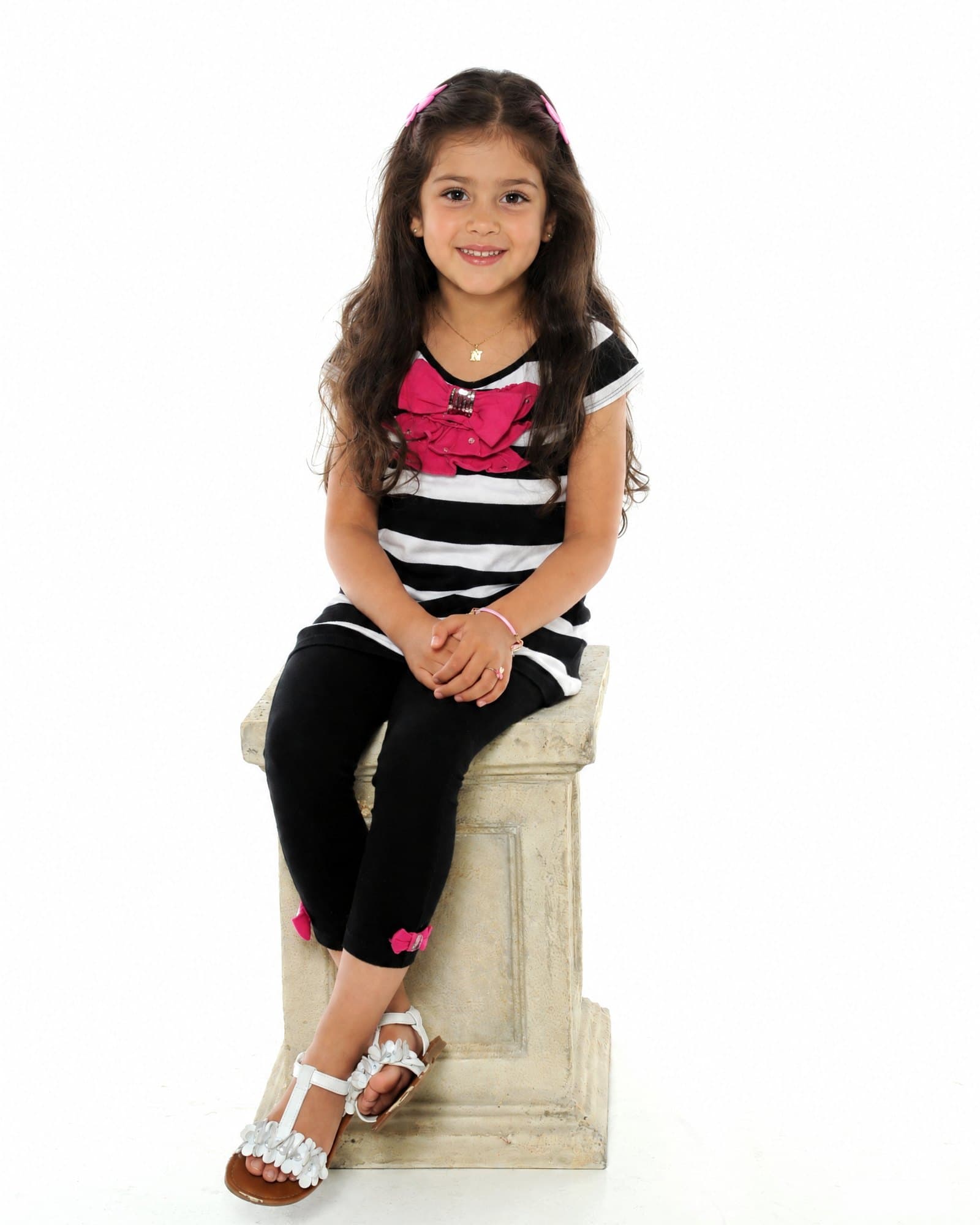 A little girl sitting on a column, on a white backdrop