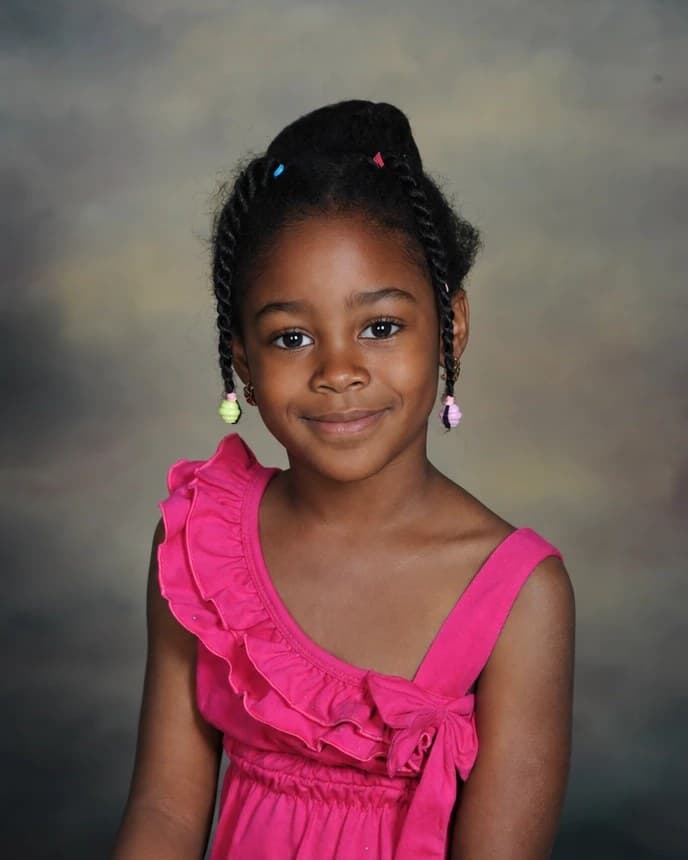 A little girl in a pink dress, her hair in braids